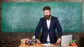 Teacher interesting interlocutor as authority. Teacher charismatic hipster stand near table classroom chalkboard