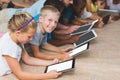 Teacher and kids lying on floor using digital tablet in library Royalty Free Stock Photo