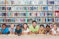 Teacher and kids lying on floor using digital tablet in library Royalty Free Stock Photo