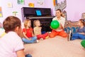 Teacher and kids sit in circle play with ball