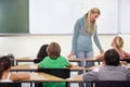 Teacher, kids and students in classroom for learning, education and math support or development at desk. Happy woman Royalty Free Stock Photo