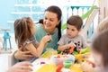 Teacher with children working with plasticine at kindergarten or playschool