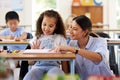 Teacher, learning and helping girl in classroom for knowledge, studying and assessment. Preschool smile, development and Royalty Free Stock Photo