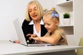 Teacher with little girl typing on the laptop in the classroom.