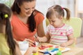 Teacher and little girls are painting in daycare center. Woman and children have a fun pastime. Royalty Free Stock Photo