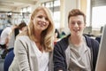 Teacher With Male Student Working On Computer In College Library