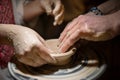 Teacher man teaches a child how to make a ceramic plate on the potters pile.