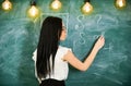 Teacher of mathematics writing on chalkboard, rear view. teacher concept. Lady teacher in glasses explaining