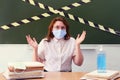 A teacher in a medical mask throws up his hands in dismay. Concept of problems with learning during coronavirus quarantine.