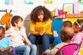 Teacher in nursery school reading a book to kids