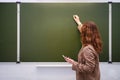 Teacher with a phone in hand writes a text in chalk on a school blackboard, copy space