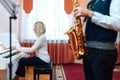 Teacher pianist plays the white piano to the accompaniment of saxophone in a music school Royalty Free Stock Photo