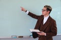 A teacher pointing at a blackboard. University professor with a black book in his hand. Master dressed in an elegant Royalty Free Stock Photo