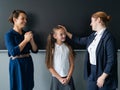 The teacher praises the schoolgirl in front of her mother standing at the blackboard.