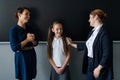 The teacher praises the schoolgirl in front of her mother standing at the blackboard.