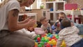 Teacher and preschool students playing with balls and cars sitting on floor at kindergarten Royalty Free Stock Photo