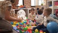 Teacher and preschool students playing with balls sitting on floor at kindergarten Royalty Free Stock Photo