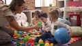 Teacher and preschool students playing with balls sitting on floor at kindergarten Royalty Free Stock Photo