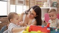 Teacher and preschool students playing with construction blocks cleaning face at kindergarten