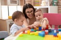 Teacher and preschool students playing with construction blocks sitting on table at kindergarten