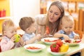 Teacher and preschooler kids having break for fruits