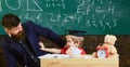 Teacher and pupil in mortarboard, chalkboard on background. Father with beard, teacher teaches bored son, little boy