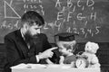 Teacher and pupil in mortarboard, chalkboard on background. Kid cheerful distracting while studying, attention deficit Royalty Free Stock Photo