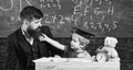 Teacher and pupil in mortarboard, chalkboard on background. Kid cheerful distracting while studying, attention deficit Royalty Free Stock Photo