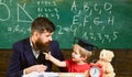 Teacher and pupil in mortarboard, chalkboard on background. Naughty child concept. Father with beard, teacher teaches Royalty Free Stock Photo