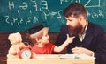 Teacher and pupil in mortarboard, chalkboard on background. Naughty child concept. Kid cheerful distracting while Royalty Free Stock Photo