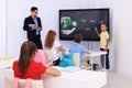 Teacher and pupil using interactive board in classroom during lesson Royalty Free Stock Photo