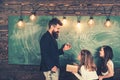 Teacher and pupils have lesson in class. Teacher write with chalk on chalkboard. Little girls listen to bearded man at Royalty Free Stock Photo