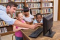 Teacher and pupils using computer at library Royalty Free Stock Photo