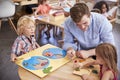 Teacher And Pupils Using Wooden Shapes In Montessori School Royalty Free Stock Photo