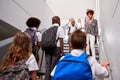 Teacher And Pupils Walking Down Stairs In Busy Elementary School Corridor