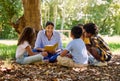 Teacher reading, tree or children with book for learning development, storytelling or growth in park. Smile, youth or Royalty Free Stock Photo