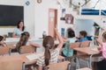 A teacher reads a book to elementary school students who listen carefully while sitting in a modern classroom Royalty Free Stock Photo