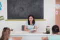 A teacher reads a book to elementary school students who listen carefully while sitting in a modern classroom Royalty Free Stock Photo