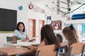 A teacher reads a book to elementary school students who listen carefully while sitting in a modern classroom Royalty Free Stock Photo