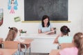 A teacher reads a book to elementary school students who listen carefully while sitting in a modern classroom Royalty Free Stock Photo