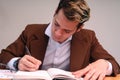 A teacher reviewing papers in the classroom. Business man dressed in cafe suit signing important papers. Man working in his office Royalty Free Stock Photo