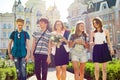 Teacher`s Day, outdoor portrait of happy middle aged female high school teacher with bouquet of flowers and group students. Royalty Free Stock Photo