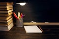 The teacher`s desk or a worker, on which the writing materials lie, a books, in the evening under the lamp. Blank for text or Royalty Free Stock Photo
