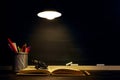 The teacher`s desk or a worker, on which the writing materials lie, a books, in the evening under the lamp. Blank for text or Royalty Free Stock Photo