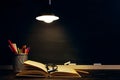 The teacher`s desk or a worker, on which the writing materials lie, a books, in the evening under the lamp. Blank for text or Royalty Free Stock Photo