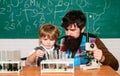 Teacher and schoolboy using microscope in class. Wunderkind. Science and education concept. Learning at home. Concept of Royalty Free Stock Photo