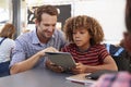 Teacher and schoolboy using tablet computer in class Royalty Free Stock Photo