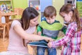 Teacher Showing a Book to Boy and Girl at the Nurcery Royalty Free Stock Photo