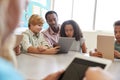 Teacher sits with young kids using computers in school class Royalty Free Stock Photo