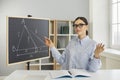 Teacher sitting desk, pointing at board and teaching students how to solve geometry problem